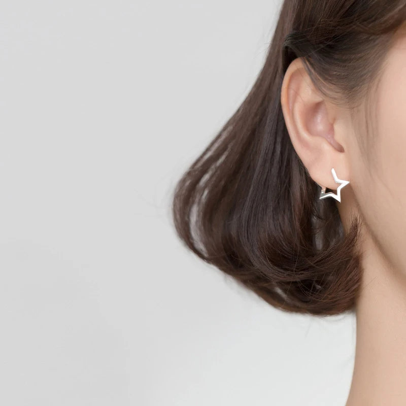 Delicate star earrings paired with classic hoop earrings