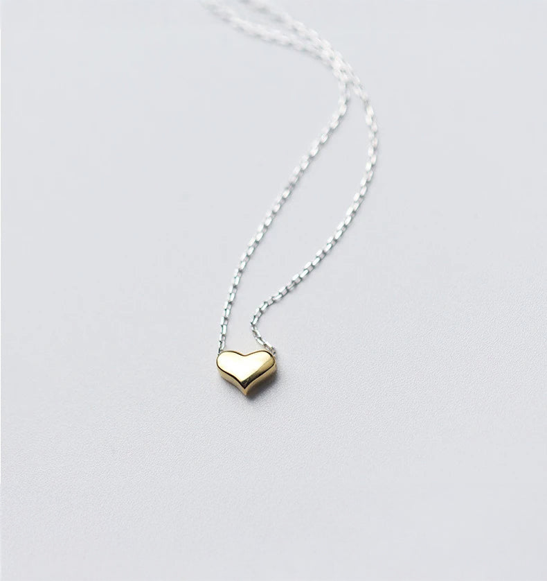 Silver chain carrying a delicate gold heart pendant necklace