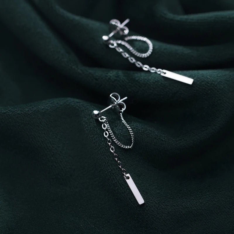 Silver earrings for women with geometric line and rose gold highlights on white background