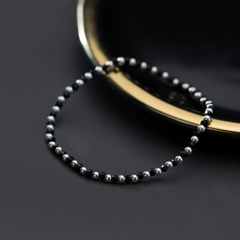 Silver bangle style bracelet featuring a single black crystal