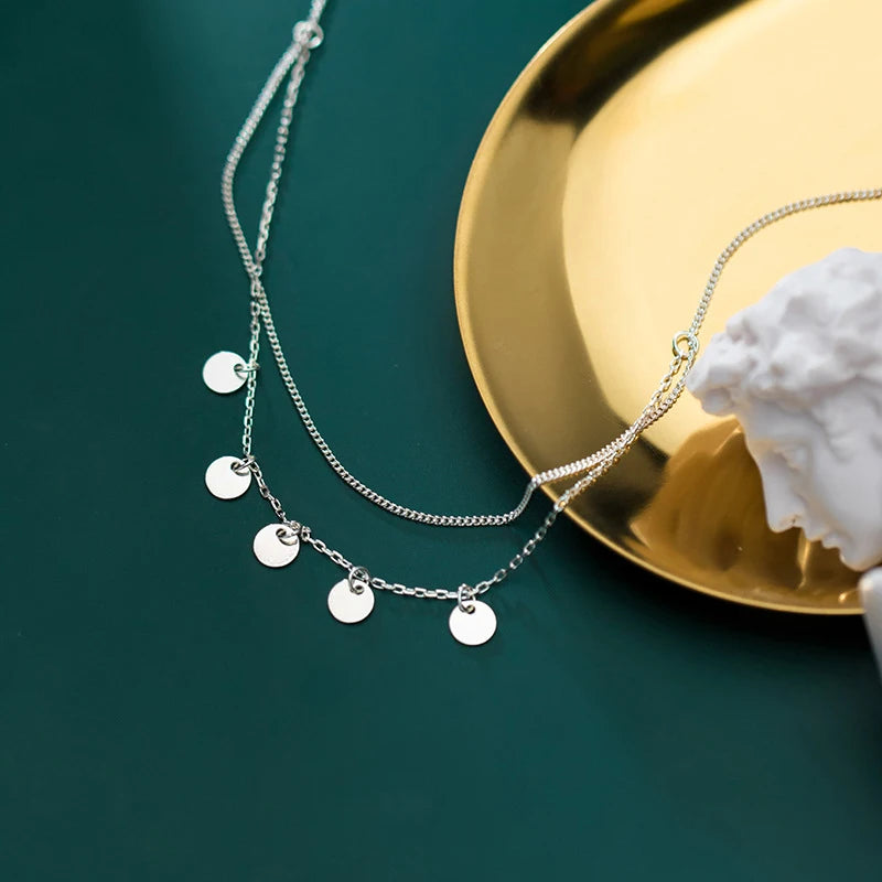 Charm necklace detail on a sleek sterling silver necklace