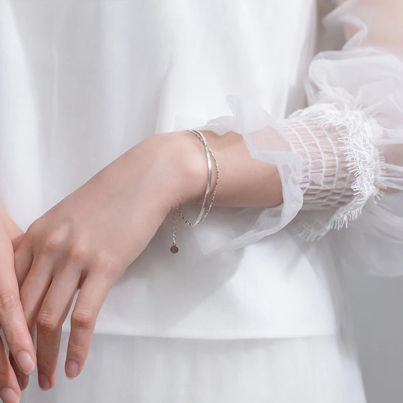 Minimal sterling silver bracelet shown beside a silver bangle