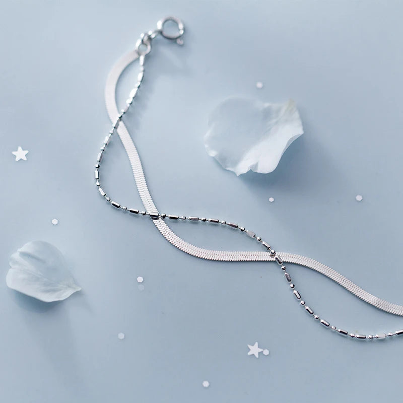 Sleek sterling silver bracelet layered with a slim chain bracelet