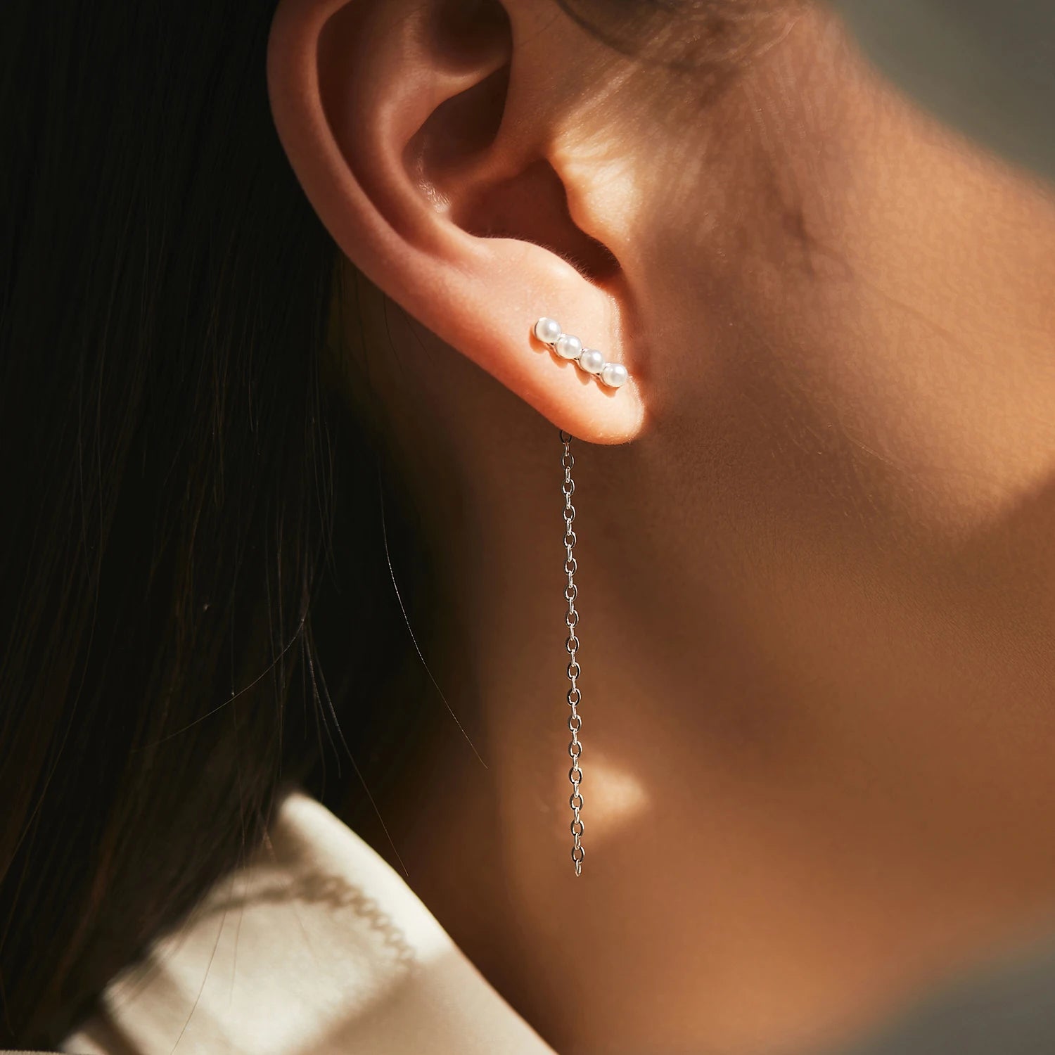 Close up of crystal and pearl dangle earrings in silver color finish