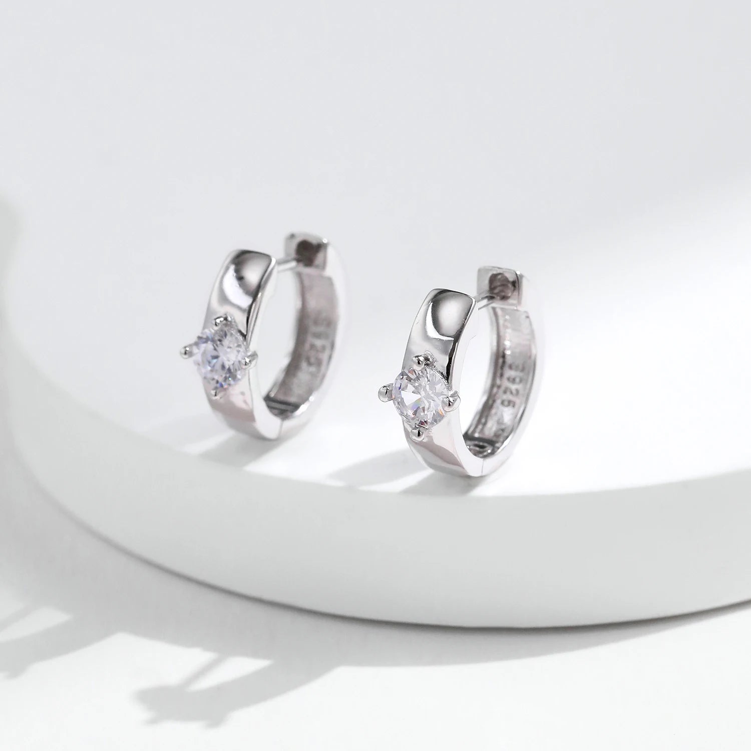 Silver hoop earrings accented by a round moissanite earring