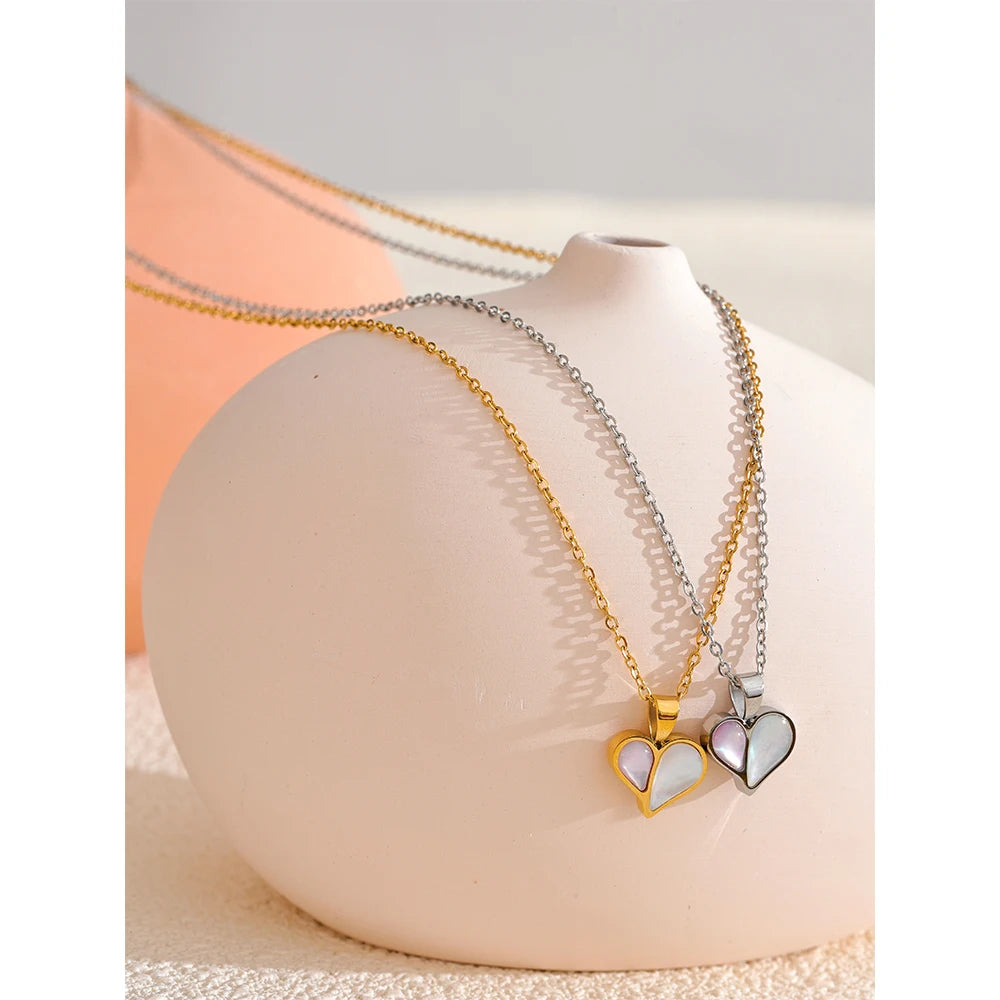 Soft light shot of a seashell necklace paired with a gold heart pendant