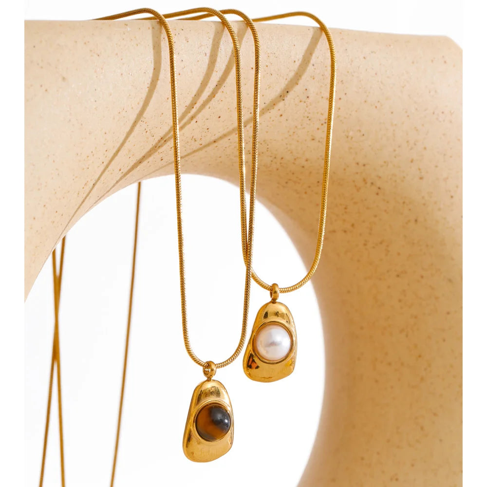 Close view of pearl on a necklace beside tiger eye stone pendant for layered shine