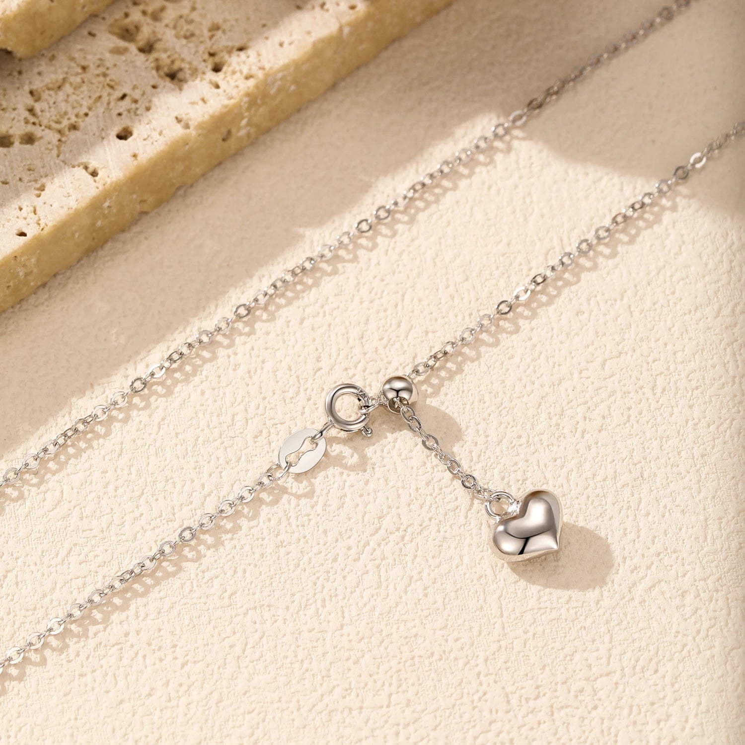 A silver necklace featuring a delicate heart in heart necklace accent