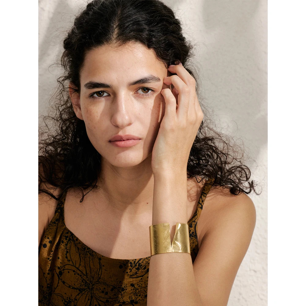 Close view of bracelet cuff showing smooth edges and reflective gold plated finish