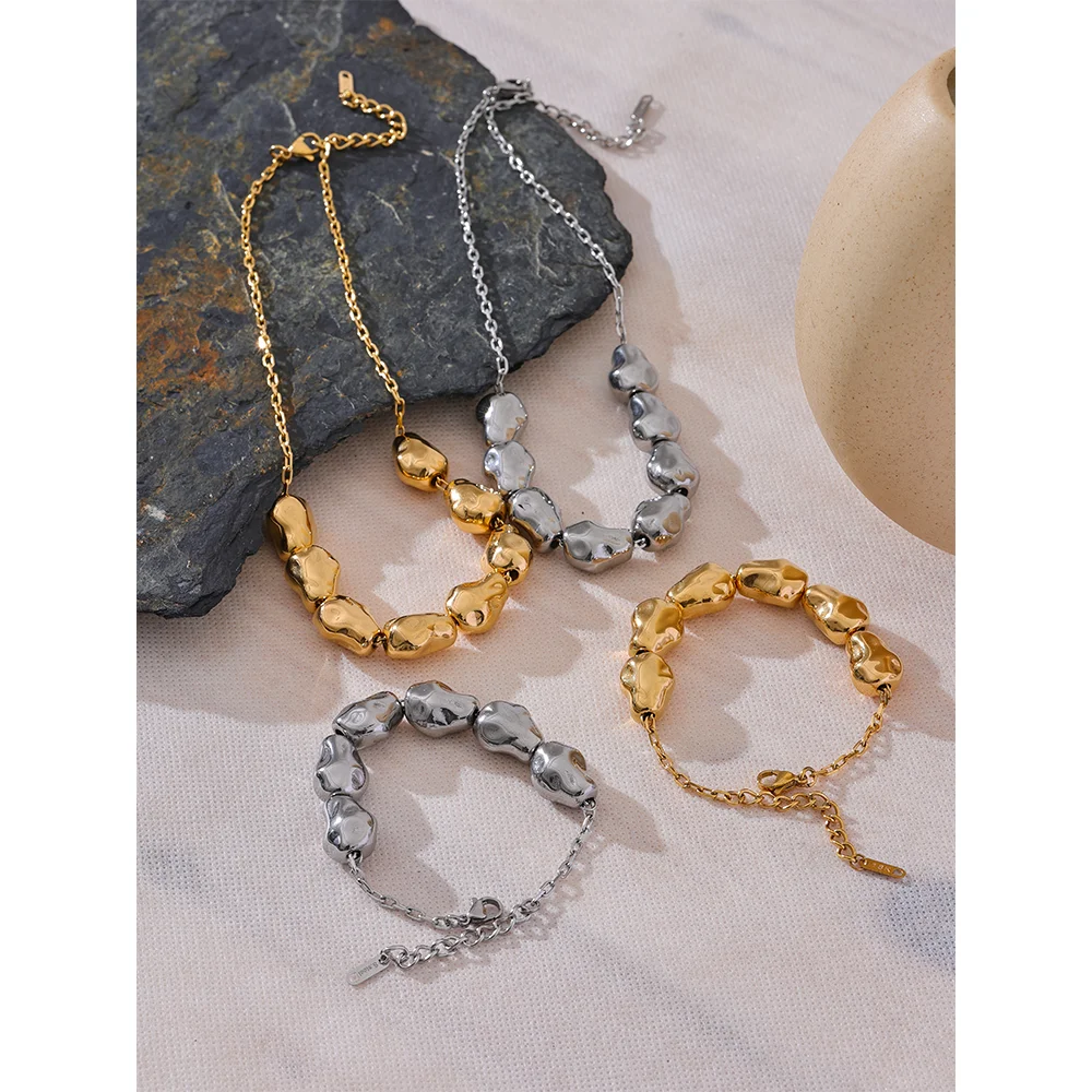 Elegant gold i necklace beside a matching bracelet gold bracelet