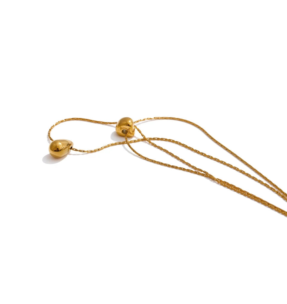 Flat lay of layer necklace beside matching charm necklace accents