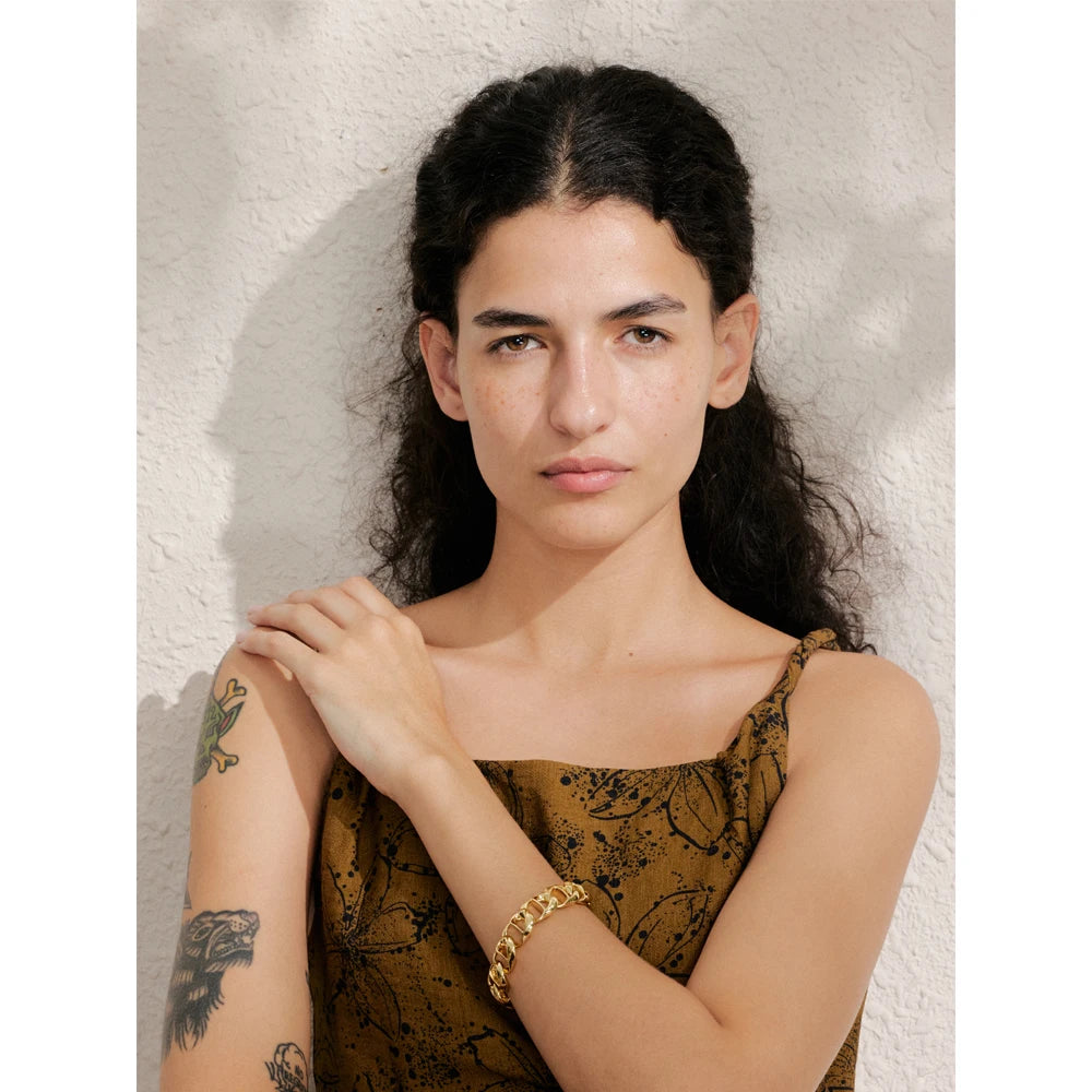 Wrist shot of women with bracelet wearing a wide chain gold plated piece