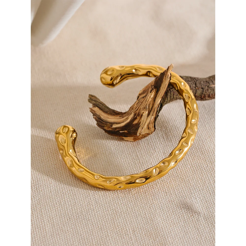 Minimal studio shot of a bracelet with gold beside a gold cuff