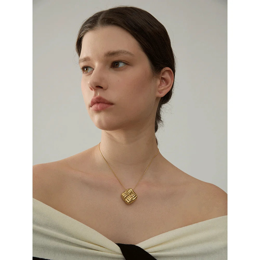 Close up of gold plated geometric pendant on chunky traverse chain