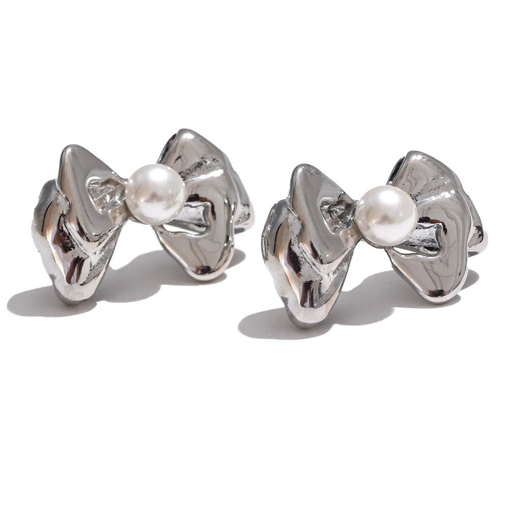 Gold earrings flat lay with bow knot and pearl accents