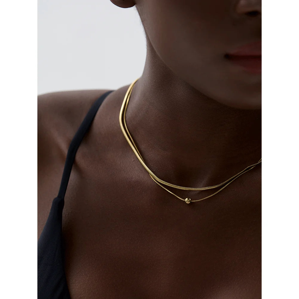 Close view of bracelet chain links beside a gold i necklace