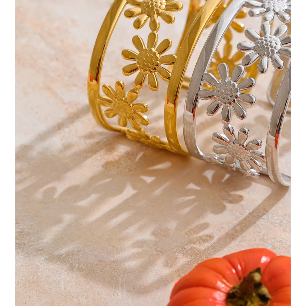 Wide gold cuff with hollow flower pattern and charm accents