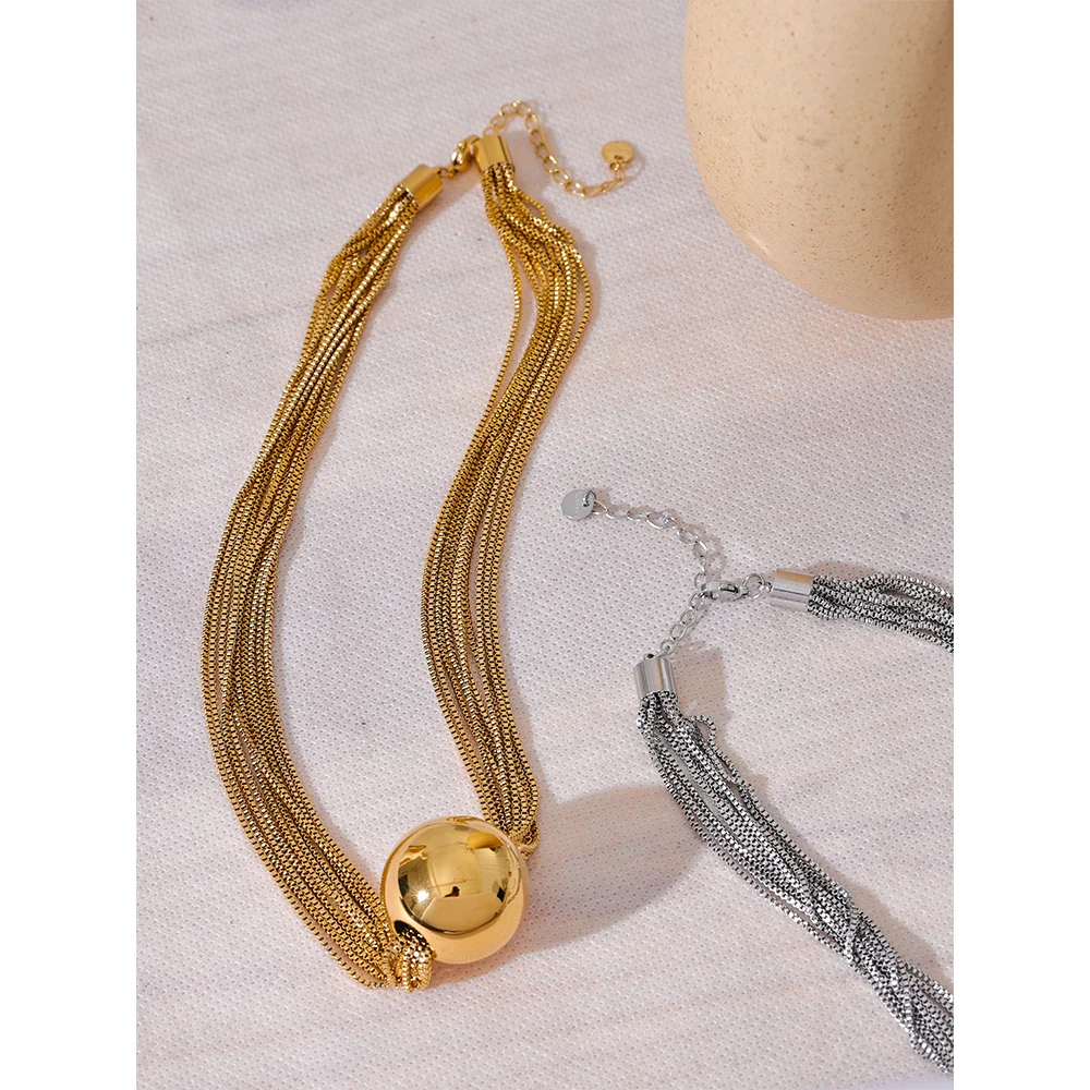 Close up of chain necklace showing layered necklace overlay and round ball pendant