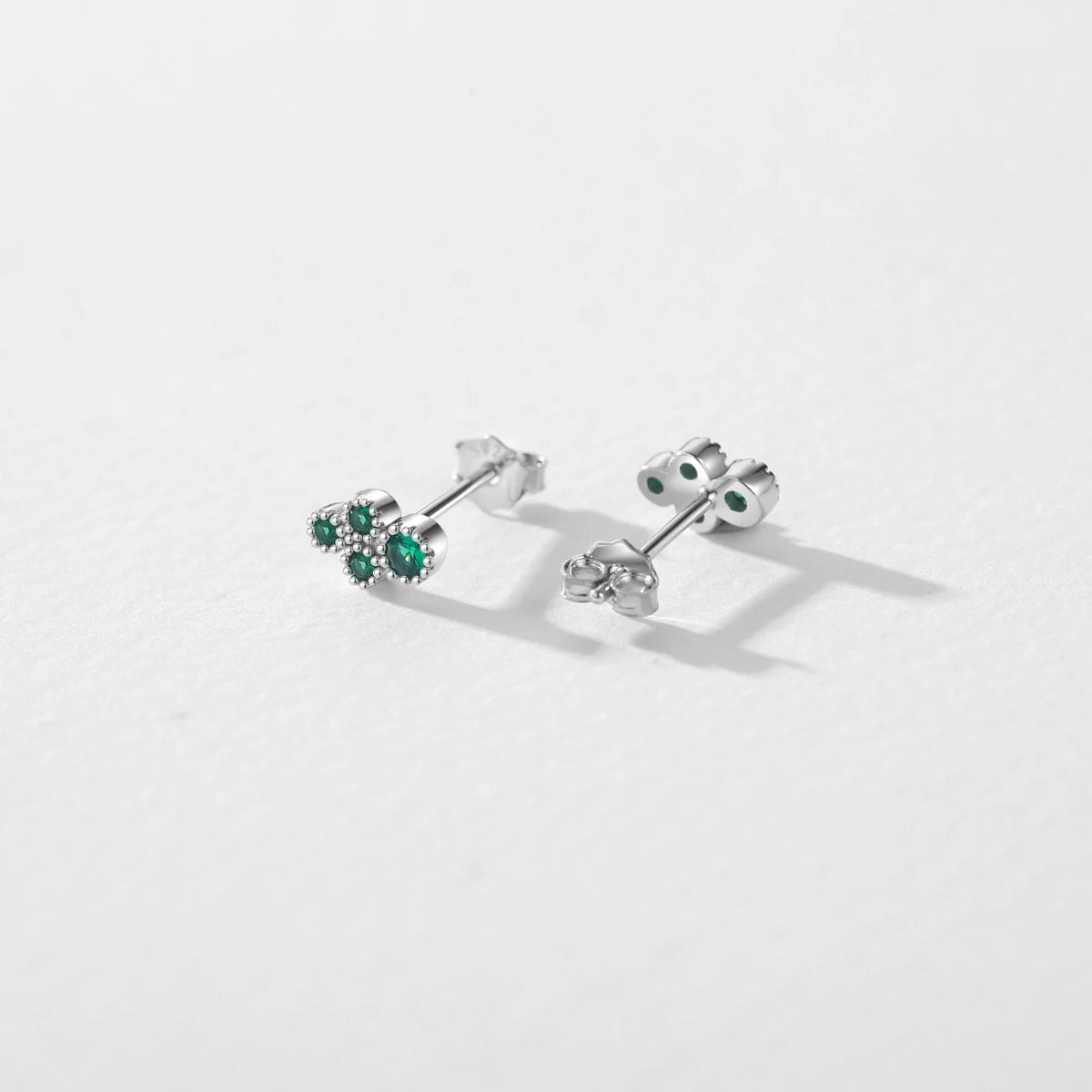 Women wearing tiny CZ stud earrings with green stone beside vintage rings for styling