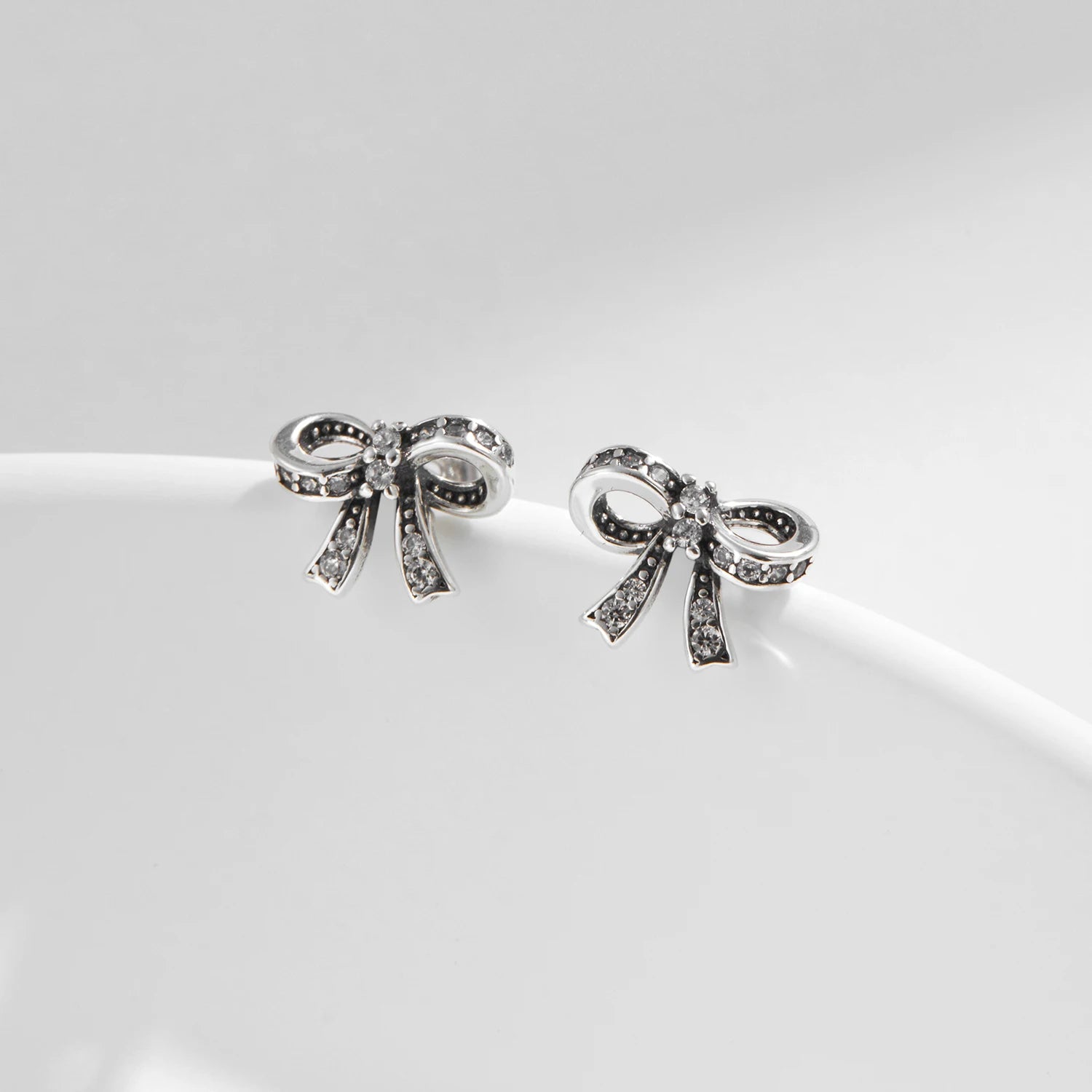 Pair of silver earrings bowknot design displayed as classic ear rings
