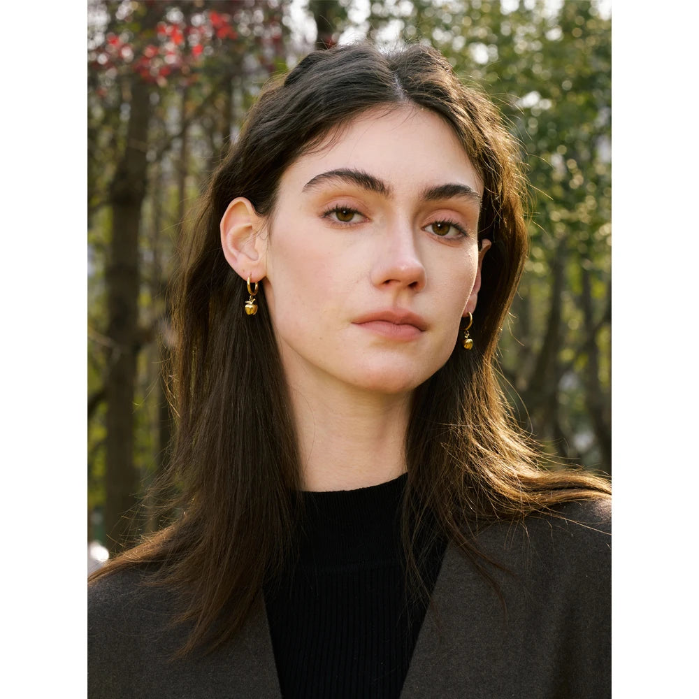 Minimal flatlay of gold necklace necklace beside apple charm accents