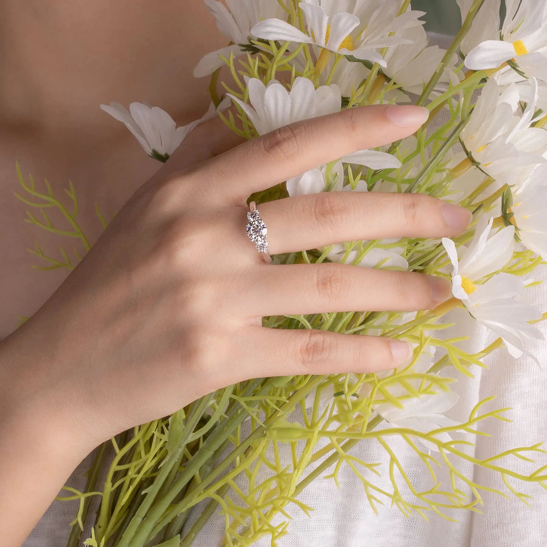 Hand wearing a white gold ring styled among rings with moissanite
