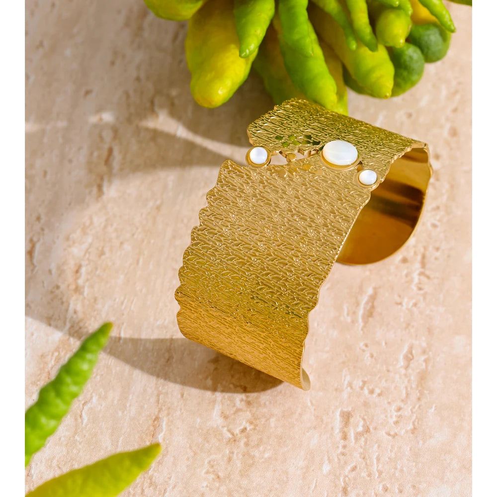 Minimal gold cuff paired with a pearl bracelet for elegant contrast