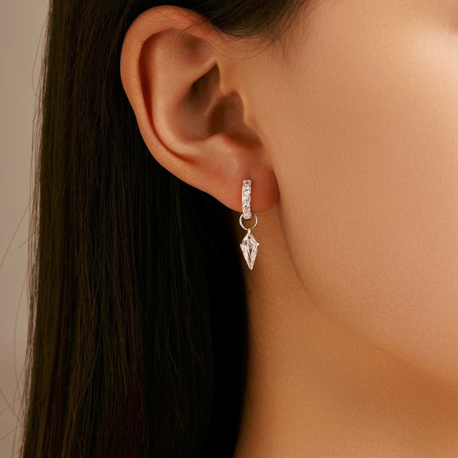 Close up of cubic zirconia studs set in rhombic silver hoop ear rings for women