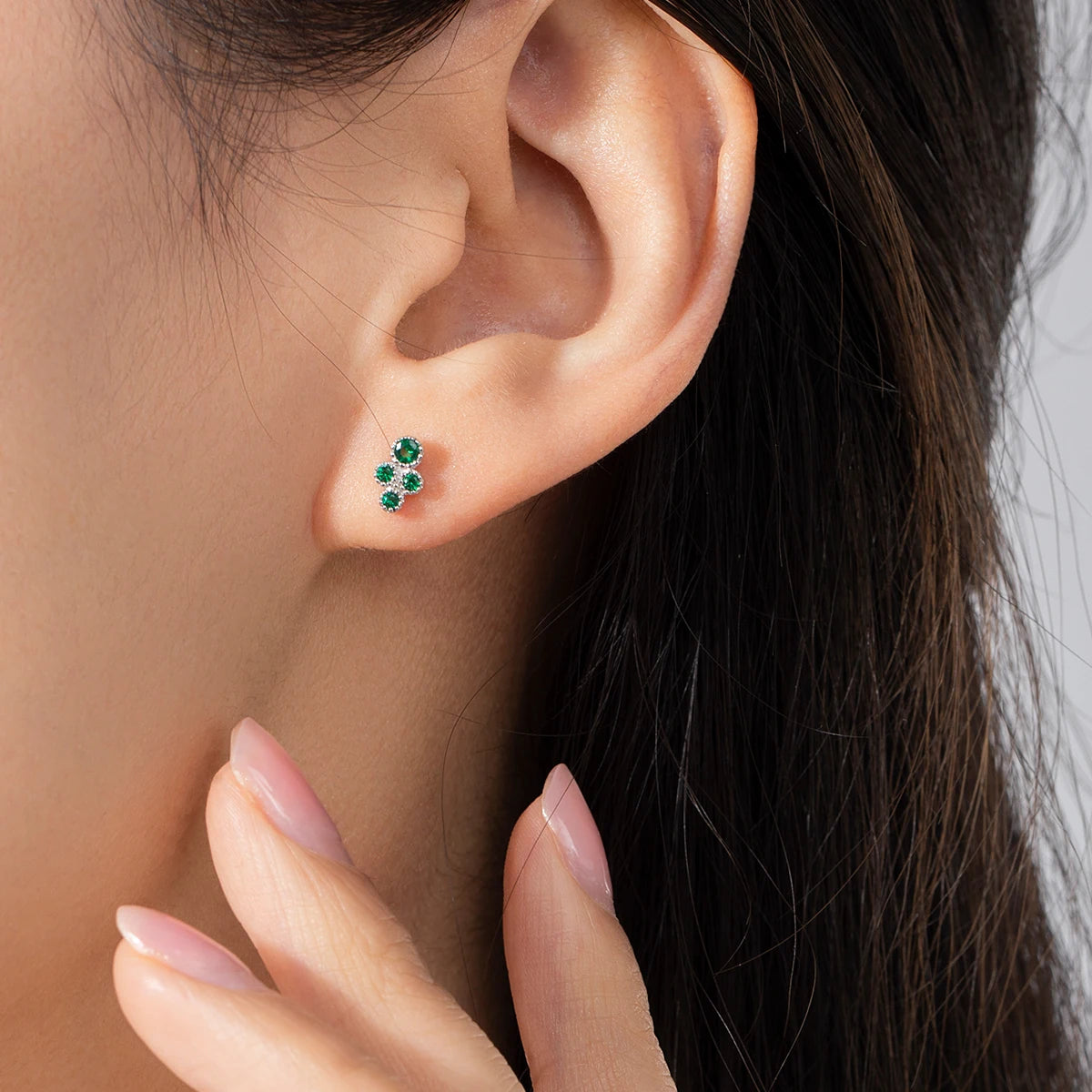 Close up of stud earrings showing clear CZ and subtle green stone in silver color setting
