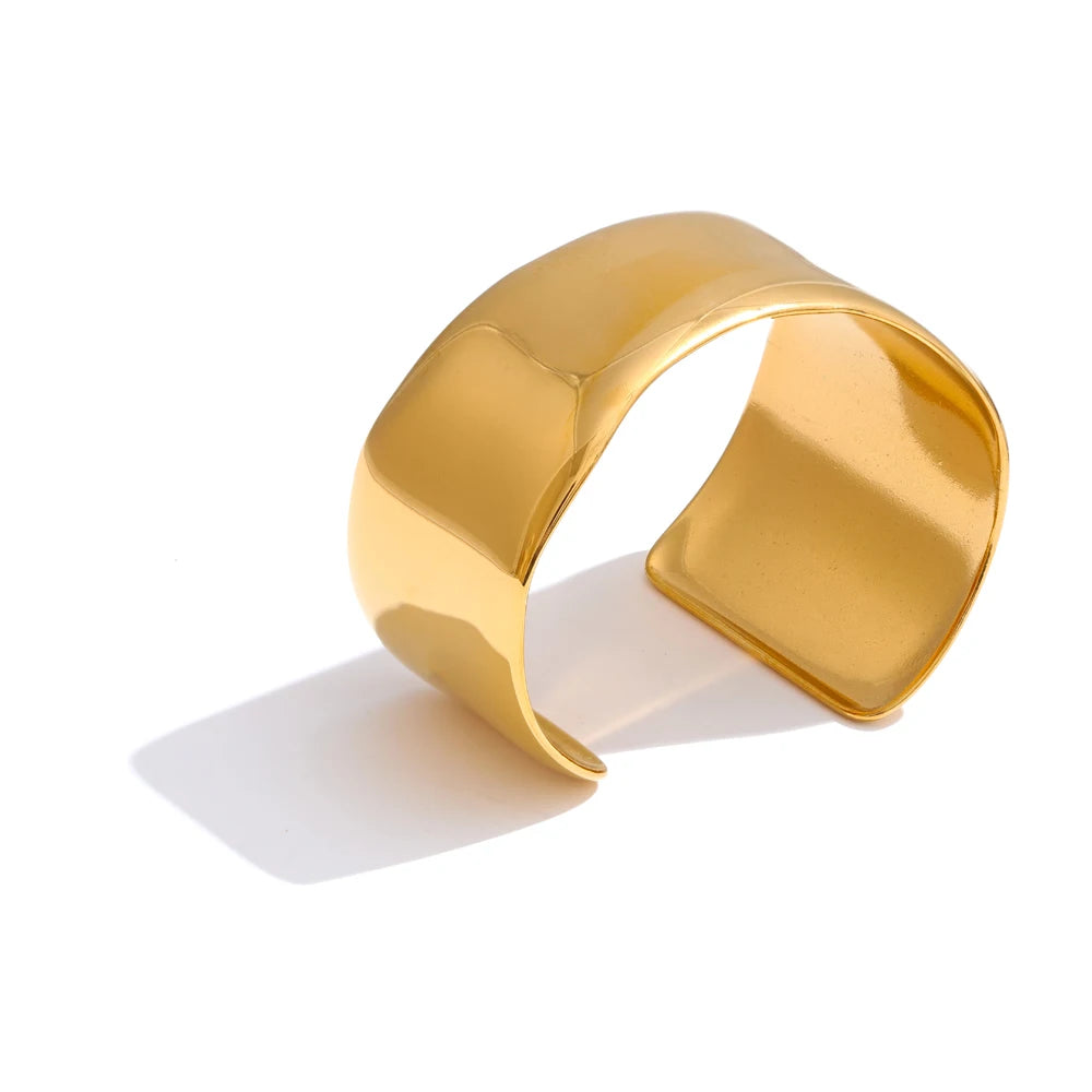 A gold bracelet in a wide cuff bracelet style with gold plated shine