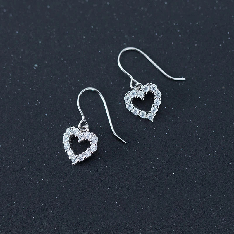 Clear CZ heart dangle earrings with charm in silver color on white background
