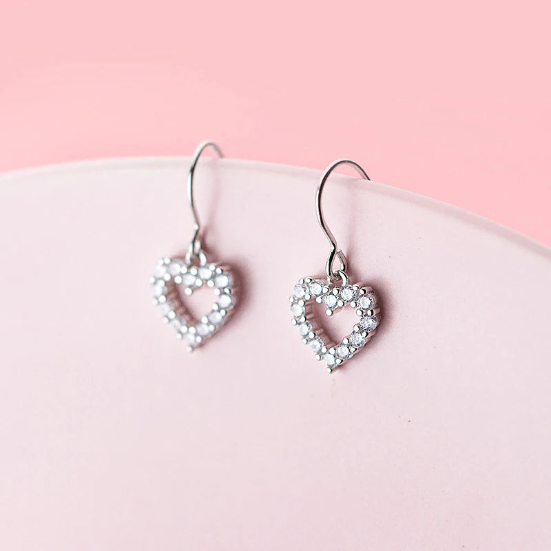 Close up of heart dangle earrings showing clear CZ stones and silver color finish