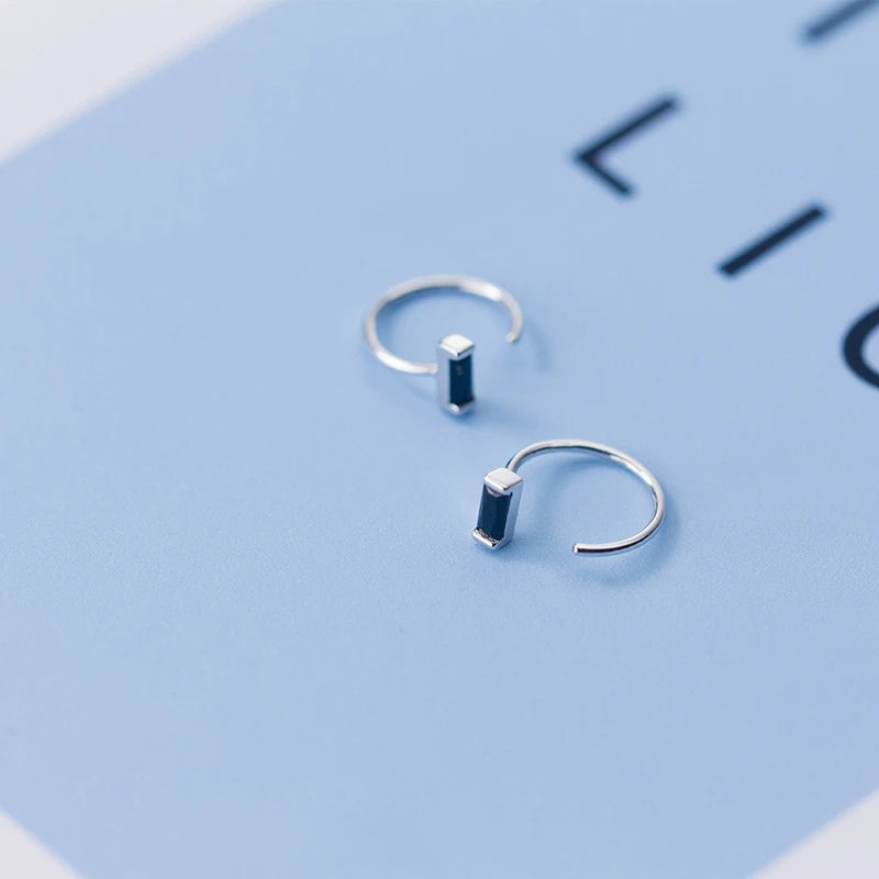 Close up of rectangular hoop earrings featuring obsidian stone and silver color