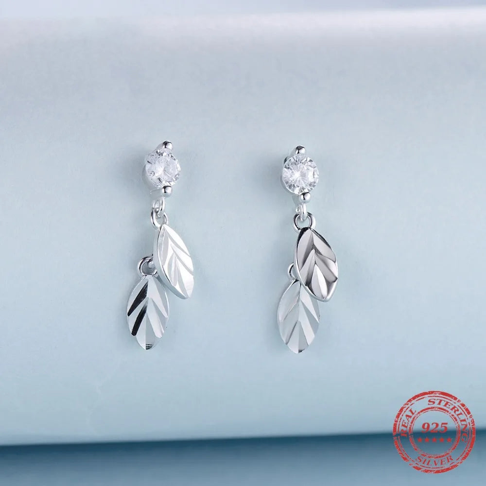 CZ earrings with leaf motif framed in silver color on white background
