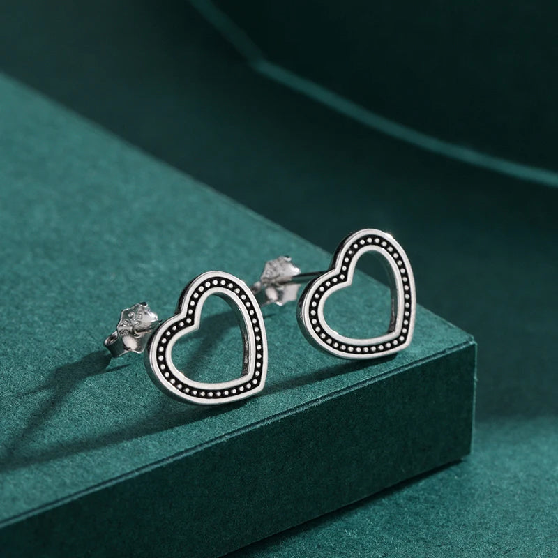 Delicate heart earrings set as stud earrings with silver color finish