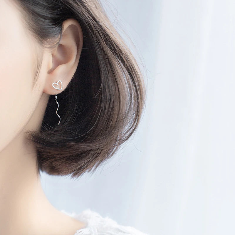 Close up of heart earrings with frosted finish and long chain drop