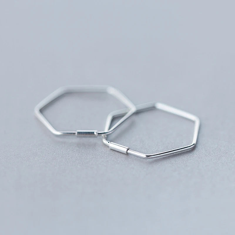 Close up of silver hoop earrings showing clean geometric lines and silver color finish