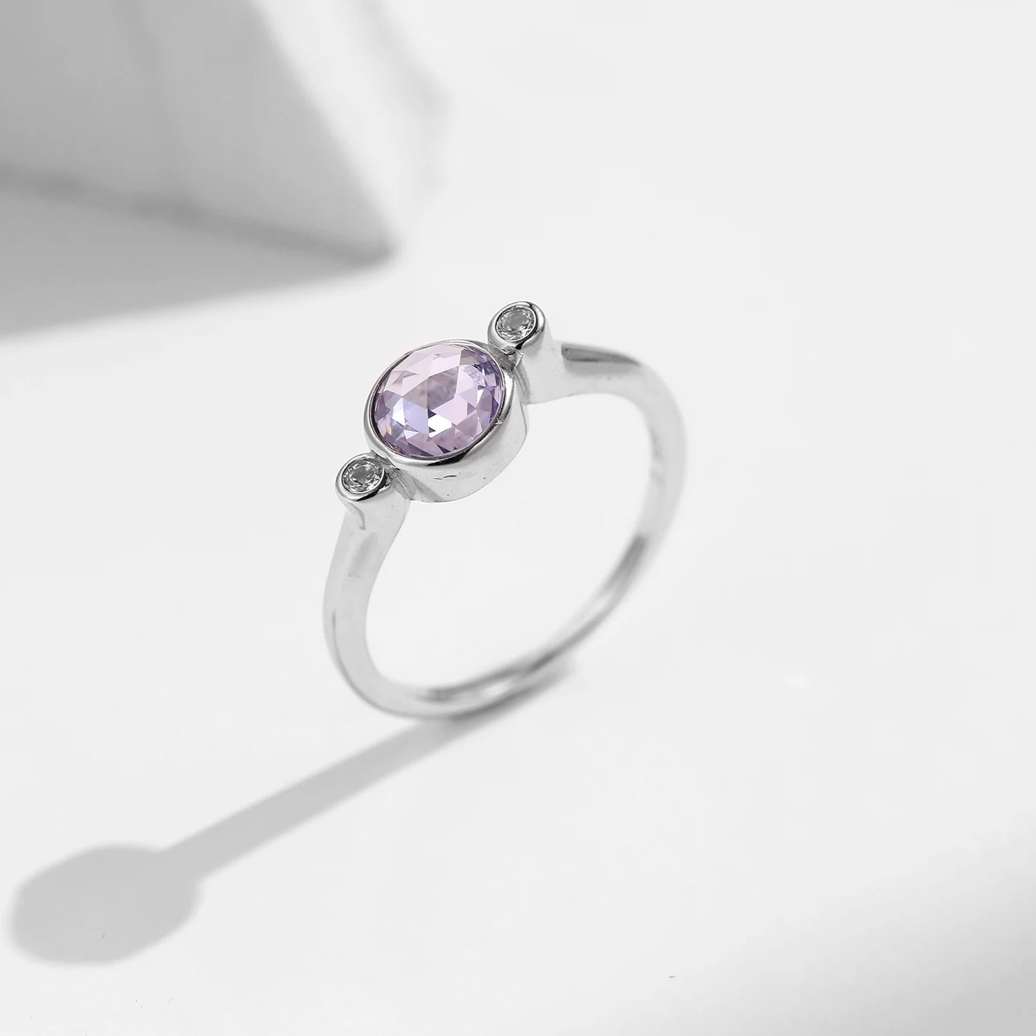 Close up silver ring with gem purple stone and ring size from ring card