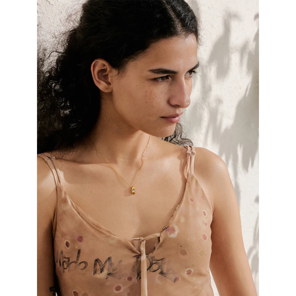 Pendant in necklace reflecting soft gold plated tone and cat eye shimmer