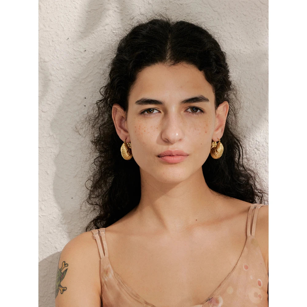 Close view of hoop earrings showing rounded shape and bright gold plated shine