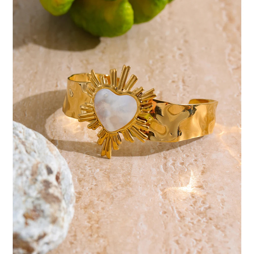 Close view of cuff bracelet showing bracelet charm heart detail and gold plated finish