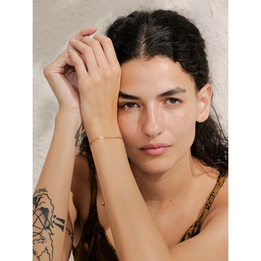 Lifestyle shot of charm bracelets paired with a sleek chain bracelet