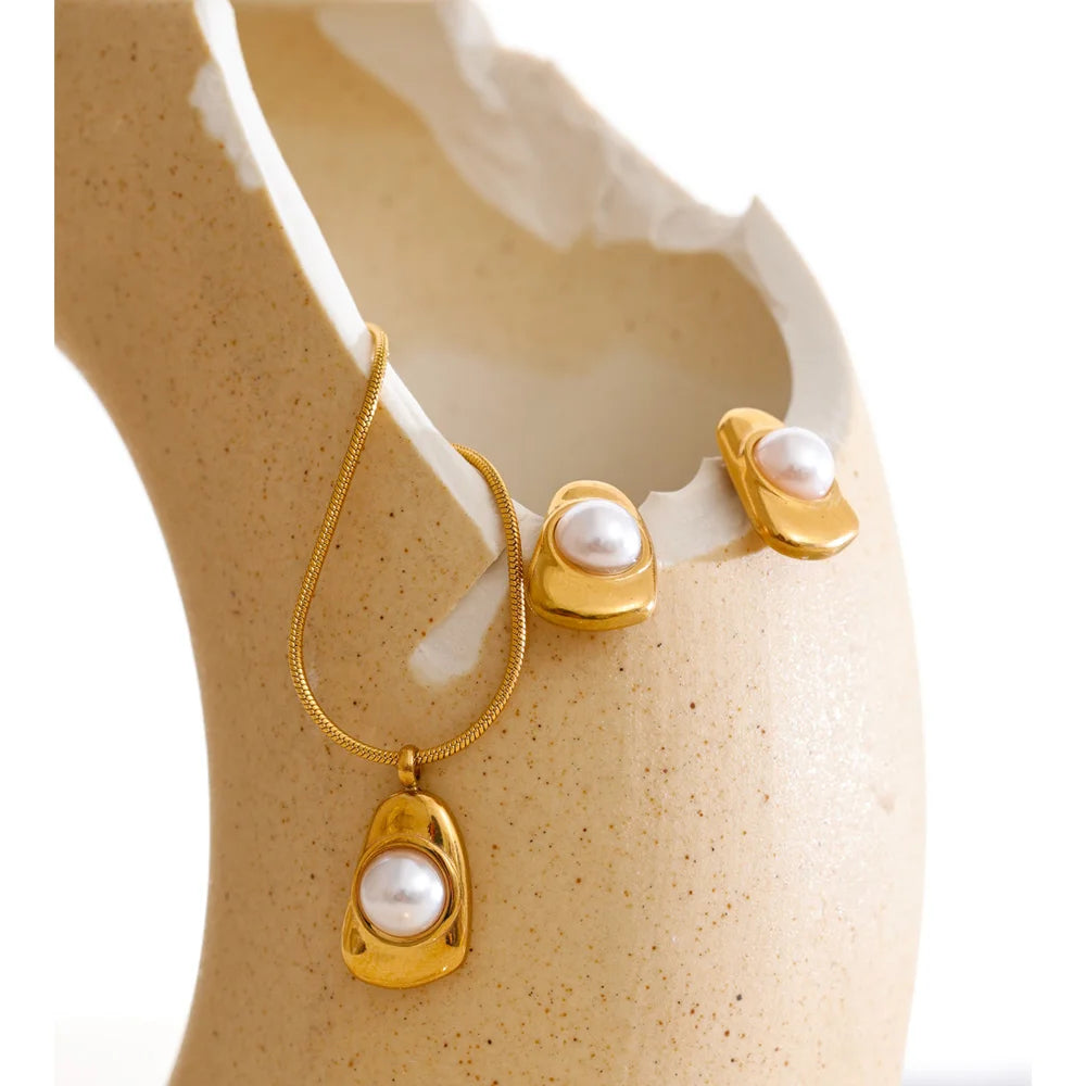 Minimal studio shot of pearl for necklace detail next to tiger eye stone centerpiece