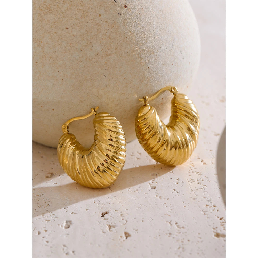 Minimal studio shot of hoop earrings paired with earrings gold earrings