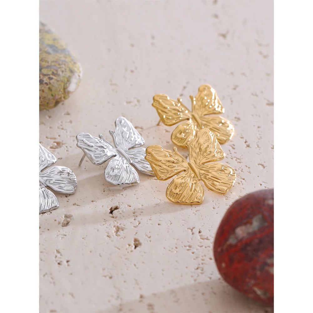 Delicate butterfly earrings shown with earrings and gold stack for daily wear