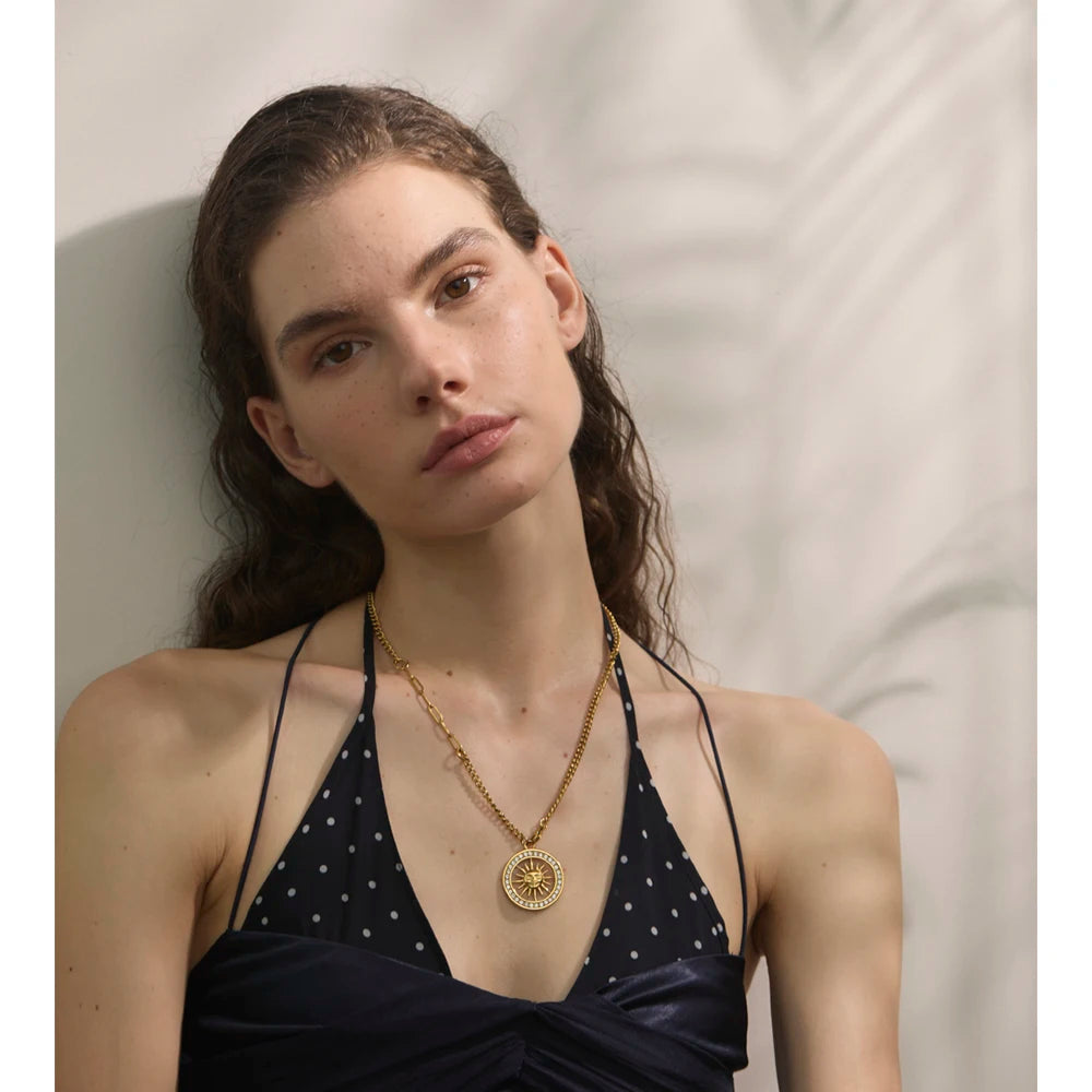 Gold jewelry chain styled as necklace and necklace with shimmering pendant