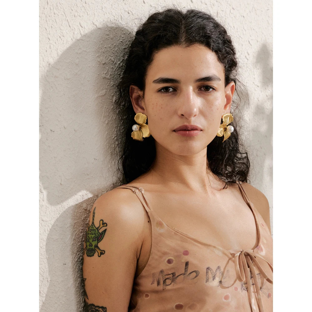 Close view showing pearl earrings set in a polished floral frame with gold and earrings glow